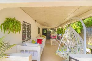 - une terrasse couverte avec des chaises blanches et une balançoire dans l'établissement Garner house watamu, à Watamu