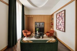a living room with a green couch and orange chairs at Park Hyatt Milano in Milan