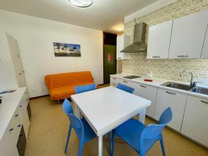 a kitchen with a white table and blue chairs at Flat in Porto Santa Margherita in Porto Santa Margherita di Caorle +12 photos