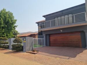 a cat laying on a driveway in front of a house at La Exotica Lodge & Spa in Rustenburg