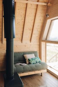 un canapé vert dans une pièce avec un poêle dans l'établissement Fontaine aux Herbes - Ecolodge Humulus lupulus, à Clarbec