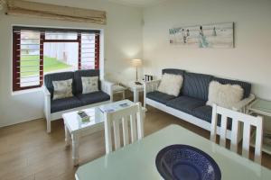 een woonkamer met een bank en een tafel bij Sea Cottage, Langebaan, 4-sleeper in Langebaan