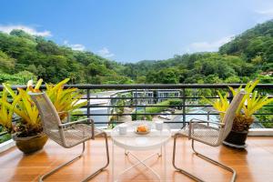einen Balkon mit einem Tisch und 2 Stühlen sowie Aussicht in der Unterkunft Hillside 2BR Apartment with Pool & Gym 5 Min to Kamala Beach 48RK in Kamala Beach