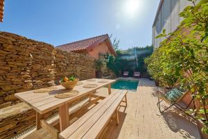 eine Terrasse mit einem Holztisch und einer Steinmauer in der Unterkunft Melro Cottage House, Douro Valley in Aldeia de Baixo