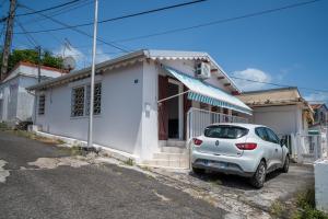 a car parked in front of a white house at Maison Yoyo - Maison Climatisée in Basse-Terre