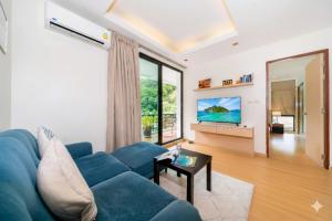 ein Wohnzimmer mit einer blauen Couch und einem großen Fenster in der Unterkunft Hillside 2BR Apartment with Pool & Gym 5 Min to Kamala Beach 48RK in Kamala Beach