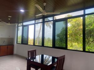 a dining room with a table and some windows at DOWN TOWN HOLIDAYS Kovalam in Kovalam