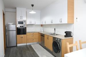 a kitchen with white cabinets and a washer and dryer at Cantinho do Sossego in Miranda do Douro