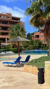 Dos tumbonas y una sombrilla en un resort. en Aphrodite Gardens Modern Apartment, en Paphos