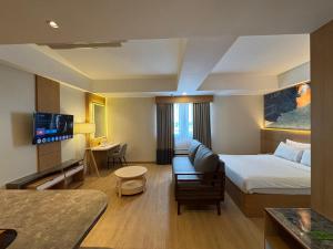 a hotel room with a bed and a couch at Metland Hotel Bekasi in Bekasi
