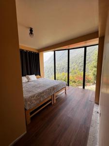Un dormitorio con una cama y una ventana grande. en TUMI Specialty Travel, en Colcapampa