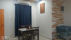 a dining room with a table and a blue curtain at Anatolia Cottage in Wakaf Baharu