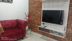 a living room with a red couch and a television at Anatolia Cottage in Wakaf Baharu