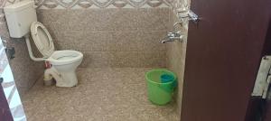 a bathroom with a toilet and a green bucket at SV HOMES Thiruvisanallur in Tribhuvanam