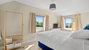 a bedroom with a bed and two windows at Rose Cottage, Bredons Norton in Bredon