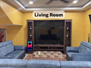 a living room with two blue couches and a television at SP Mawar Guest House in Kampong Ulu Melaka Pindah