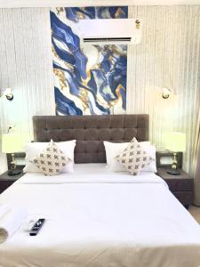 une chambre avec un grand lit blanc avec un tableau sur le mur dans l'établissement Hotel Fortune Home E-46 Noida Sector 72, à Noida