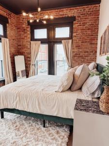 a bedroom with a brick wall and a large bed at The Cozy Corner - Downtown Troy in Troy