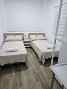 two beds in a room with wooden floors at Apartamentos vacacionales malba in Punta Umbría