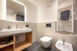 a bathroom with a sink and a toilet and a mirror at Apartments Raffl in San Pietro in Gardena +26 photos