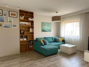 a living room with a blue couch and a book shelf at Apartament Przestronny in Puck