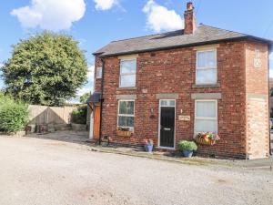 una casa in mattoni rossi con fiori sul portico di Corner House Cottage a Ilkeston