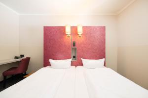 a bedroom with a large white bed with a red wall at Hotel Topas Frankfurt City Centre - Digital Check-In in Frankfurt