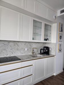 Una cocina con gabinetes blancos y un fregadero. en Sol Marina Apartament Marina Blue, en Wiślinka
