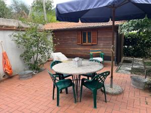 a table with chairs and an umbrella on a patio at Una casa ospitale con giardino in Castel SantʼAngelo