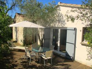 a patio with a table and chairs and an umbrella at Le mazet d'Uzès in Uzès