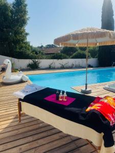 a pool with a table and an umbrella next to it at Gîte Les Lauriers Roses in Marseillan