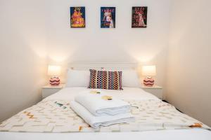 een slaapkamer met een wit bed met drie schilderijen aan de muur bij The Didsbury Loft in Manchester