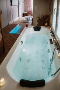 e bagno con vasca riempita d'acqua. di La Parenthèse Fleurie - Suite avec balnéo au coeur de Bergerac a Bergerac
