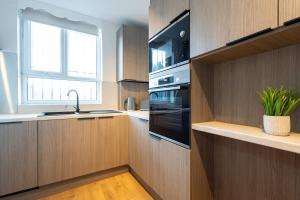 eine Küche mit Holzschränken und Spüle und einem Fenster in der Unterkunft The Withington in Manchester