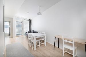 ULEABO New and bright downtown 3-room apartment في أولو: غرفة معيشة بيضاء مع طاولة وكراسي +9 صور