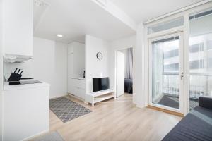 ULEABO New and bright downtown 3-room apartment في أولو: غرفة معيشة بيضاء مع نافذة كبيرة وتلفزيون