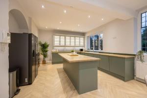 a large kitchen with green cabinets and a large island at The GreyStoke Mansion With Private Grounds in Hale