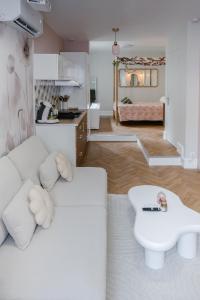 un soggiorno con un divano bianco e un tavolo di La Parenthèse Fleurie - Suite avec balnéo au coeur de Bergerac a Bergerac
