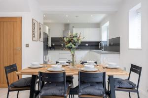 a dining room table with chairs and a vase of flowers at The Wilmslow House Free Parking - Close to Airport in Alderley Edge