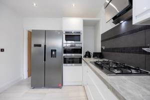 a kitchen with a stainless steel refrigerator and stove at The Wilmslow House Free Parking - Close to Airport in Alderley Edge