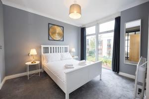 a bedroom with a white bed and a large window at The Sharston - Free Parking & Close To Airport in Wythenshawe +5 photos