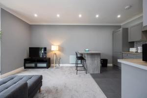 a living room with a couch and a kitchen at The Sharston - Free Parking & Close To Airport in Wythenshawe