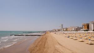 a beach with chairs and umbrellas and the ocean at Hotel Venezuela in Lido di Jesolo