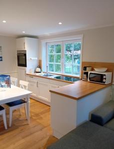 a kitchen with white cabinets and a table with a microwave at Nebel-s-Hues-Eg in Nebel
