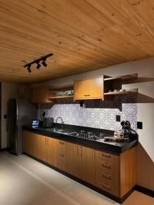 una cucina con armadi in legno e piano di lavoro nero di Cabana Molina - Ofurô, Lareira e Vista Única a Pirenópolis