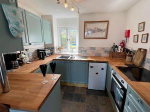 a kitchen with blue cabinets and two wine glasses on the counter at The Cowshed, near Conwy in Conwy