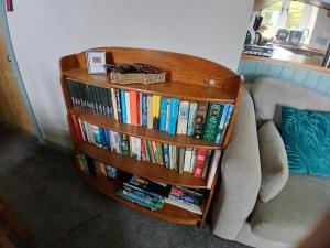 a book shelf filled with books next to a couch at The Cowshed, near Conwy in Conwy