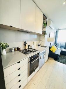 a kitchen with a stove top oven next to a couch at ADEK Apartments North Melb - 2BR Apt near Melb Zoo with free Parking, Pool & Gym in Melbourne