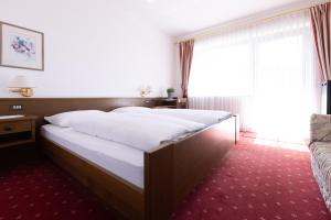 a bed in a hotel room with a large window at Pension Kleon in Rifiano