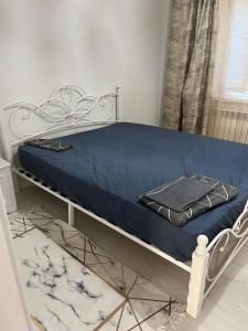 a white bed with a blue blanket on it at Asman Loft in Uralsk